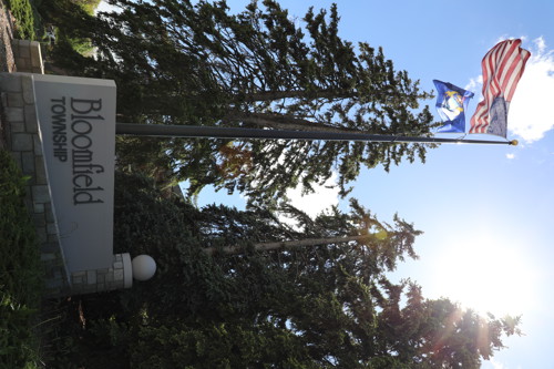 Outdoor Signage that reads Bloomfield Township in front of a flagpole with American flag and Michigan flag