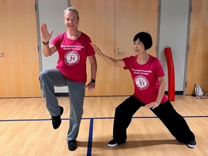 2 women wearing BTSS t-shirts doing a tai chi pose