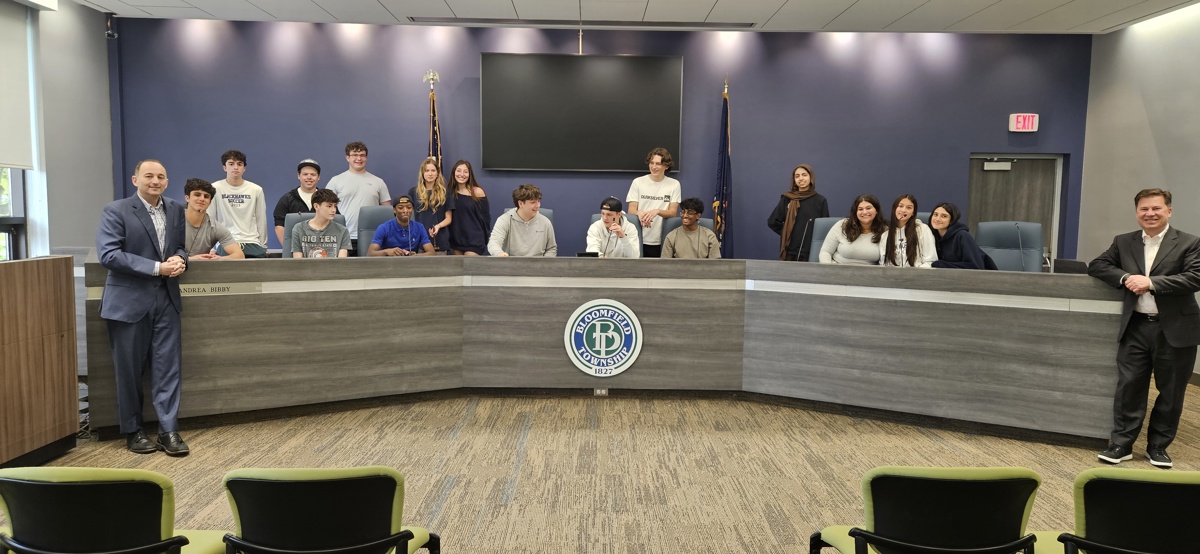 High School Civics Class students gathered behind the dais in the Bloomfield Township Hall Auditorium with Treasurer Schostak and Clerk Brook on either side